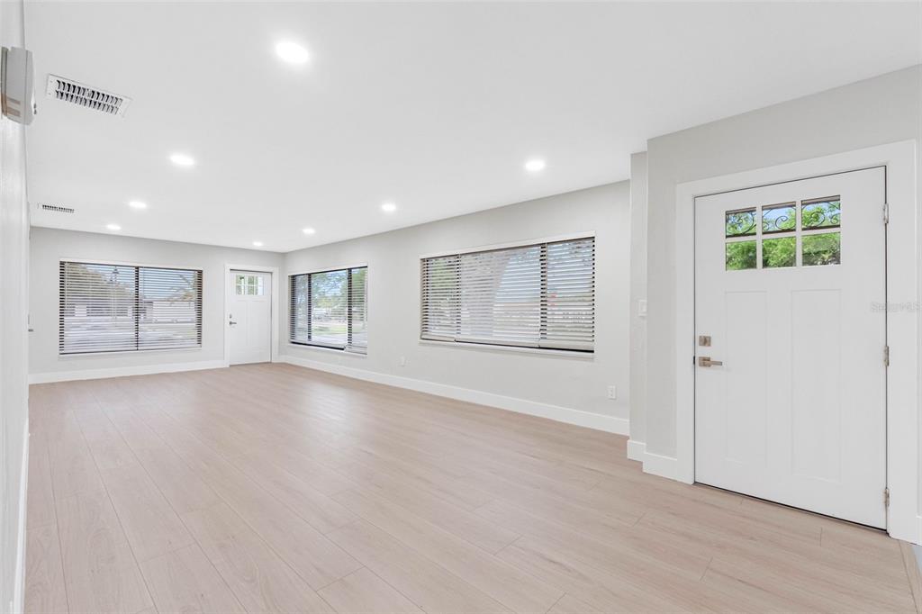 An empty room with light wood-look flooring, white walls, recessed lighting, and a white door — 1005 APACHE TRAIL, CLEARWATER, FL