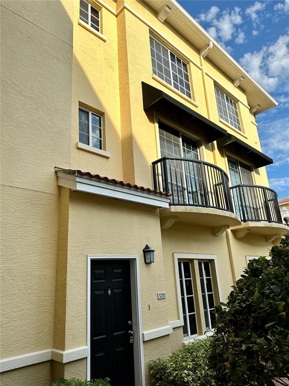 A yellow three-story townhouse features a black front door and two small balconies — 5213 BEACH BREEZE COURT, TAMPA, FL