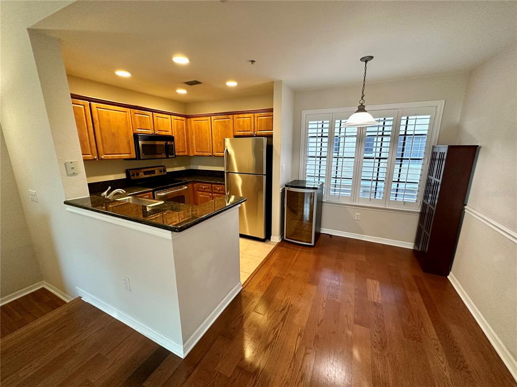A kitchen with wood cabinets, stainless steel appliances, and a breakfast bar overlooks a dining area — 5213 BEACH BREEZE COURT, TAMPA, FL