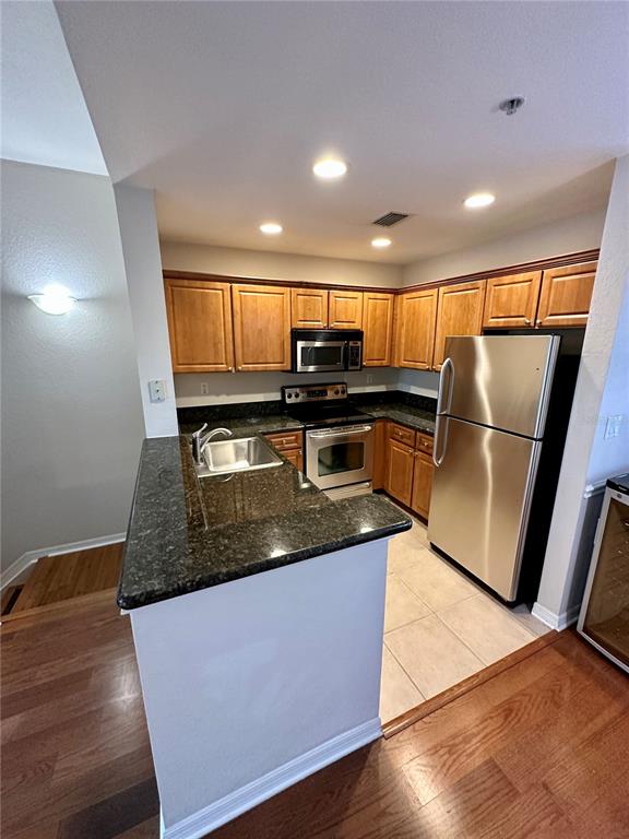 A kitchen features wood cabinets, dark granite countertops, and stainless steel appliances — 5213 BEACH BREEZE COURT, TAMPA, FL