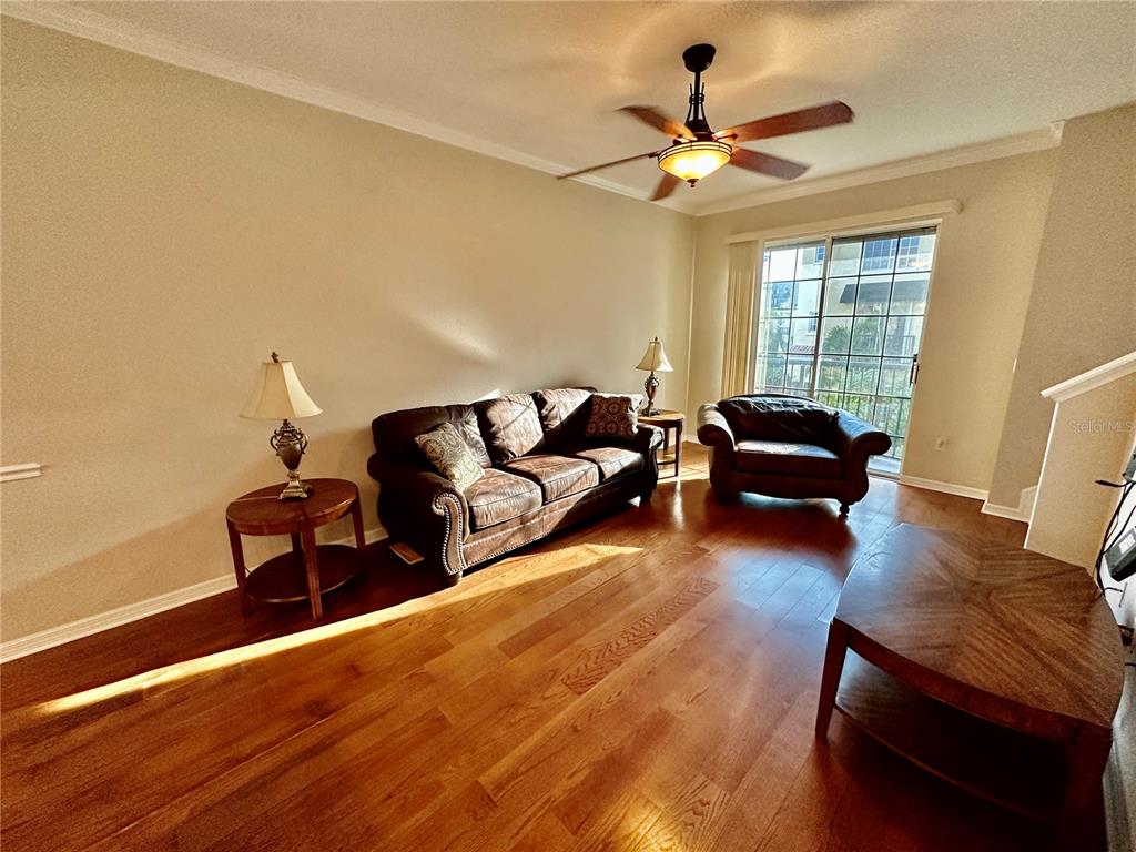 A living room features hardwood floors, a leather sofa, an armchair, and a ceiling fan — 5213 BEACH BREEZE COURT, TAMPA, FL