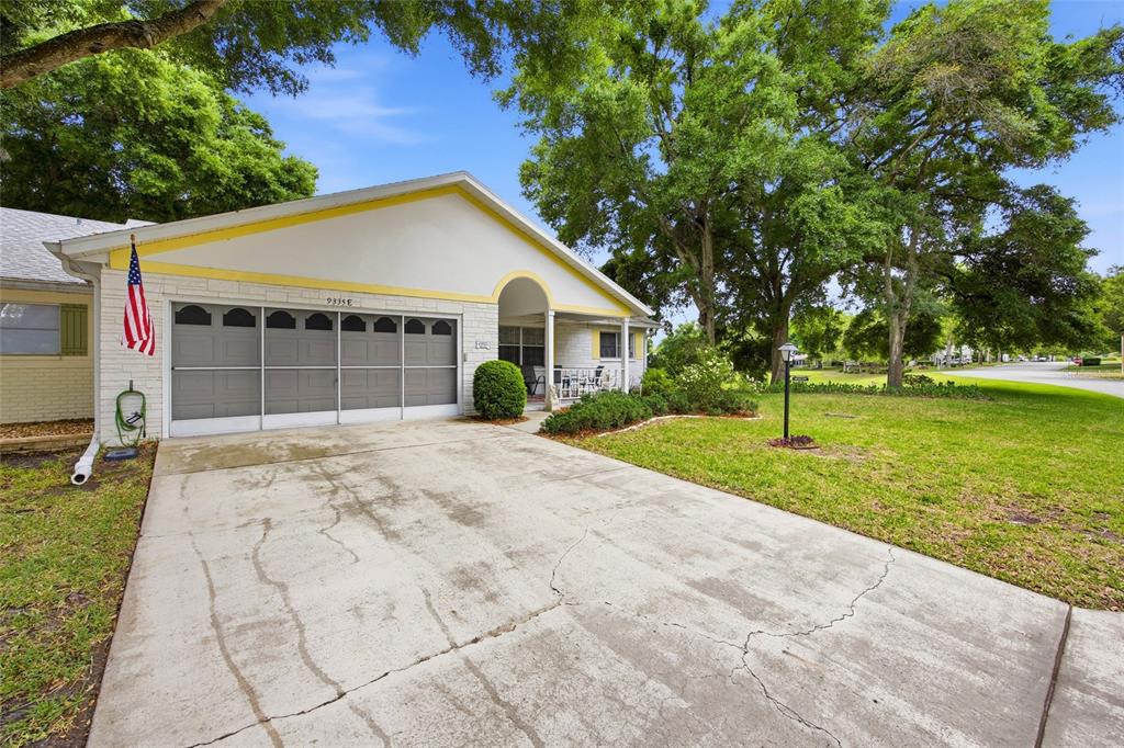 A living room features light wood flooring, a gray reclining sofa, and a mirrored wall — 9335 SW 85TH TERRACE UNIT E, OCALA, FL