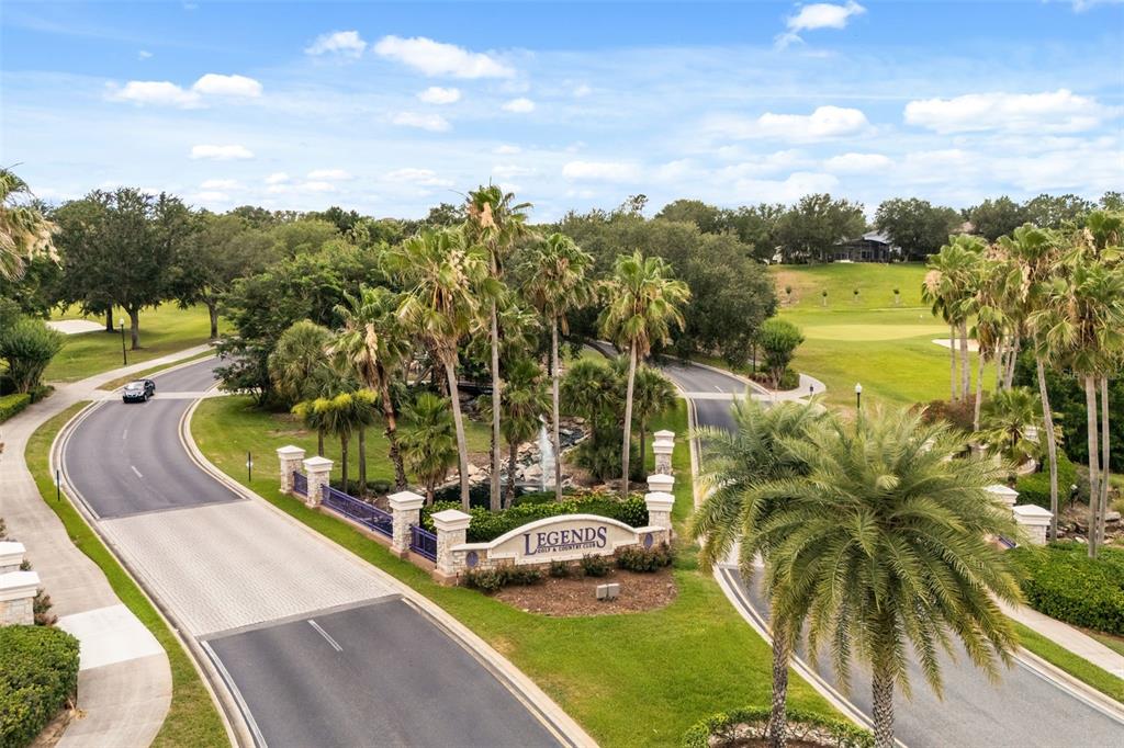 An aerial view shows the entrance sign for a golf and country club with palm trees — 4332 FAWN MEADOWS CIRCLE, CLERMONT, FL