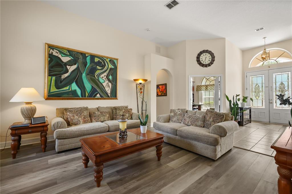 A living room features two beige sofas, a wooden coffee table, and large wall art — 4332 FAWN MEADOWS CIRCLE, CLERMONT, FL