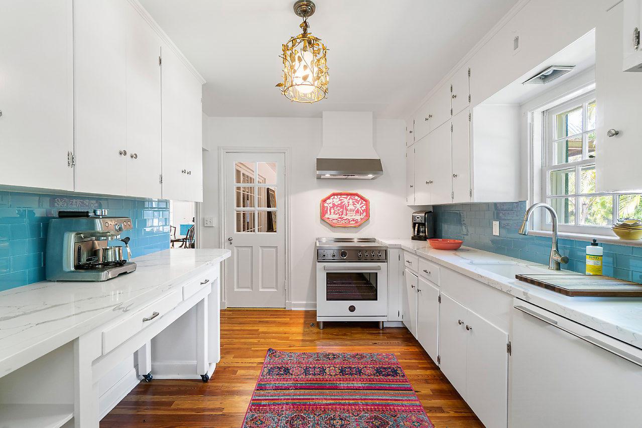 A kitchen features white cabinets, blue subway tile backsplashes, marble countertops, and a colorful rug — 1008 N Ocean Boulevard, Gulf Stream FL 33483, GULF STREAM, FL