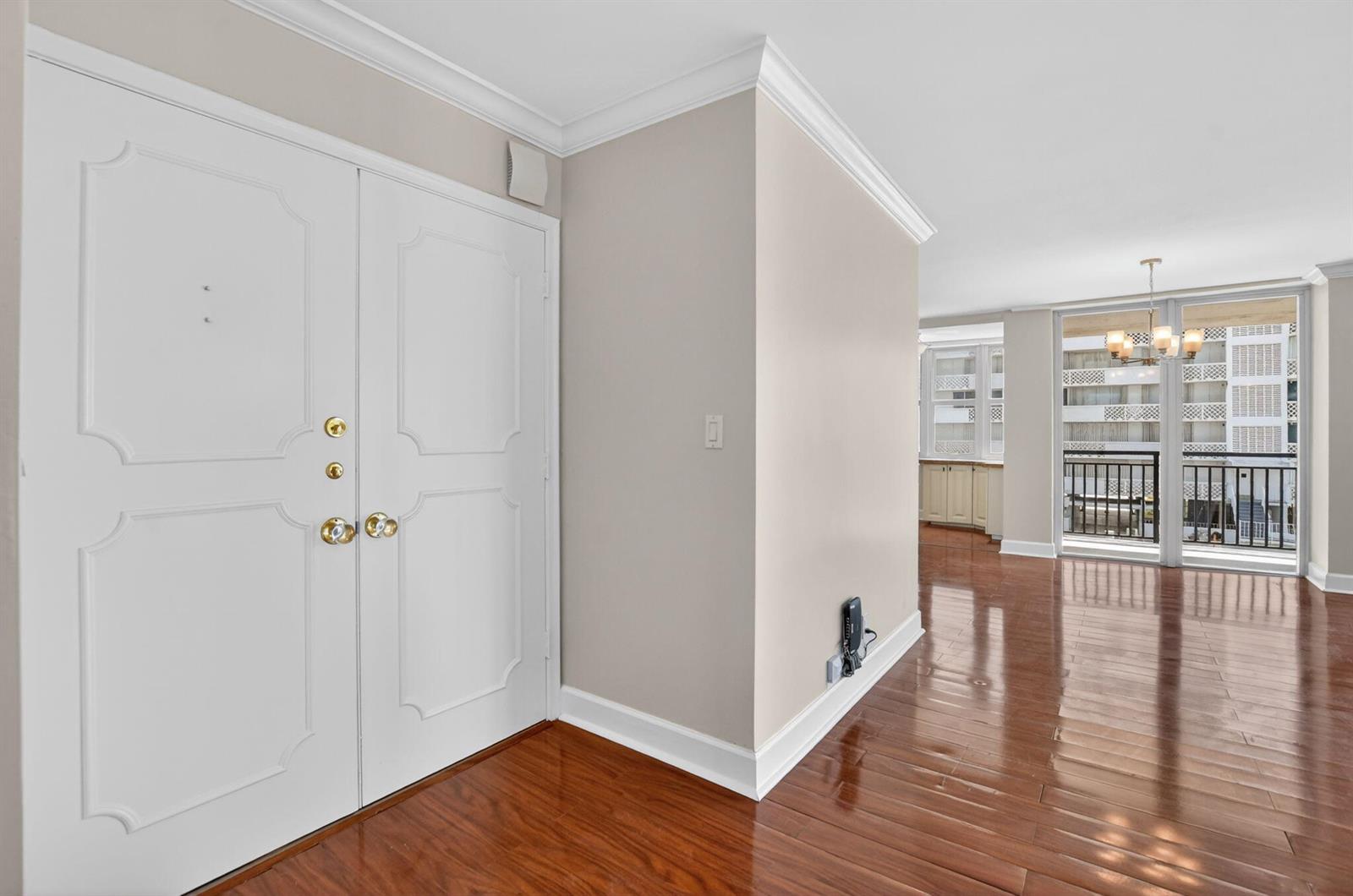 A room with hardwood floors, white double doors, and a balcony view of a building — 1180 S Ocean Boulevard # 3f, Boca Raton FL 33432, BOCA RATON, FL