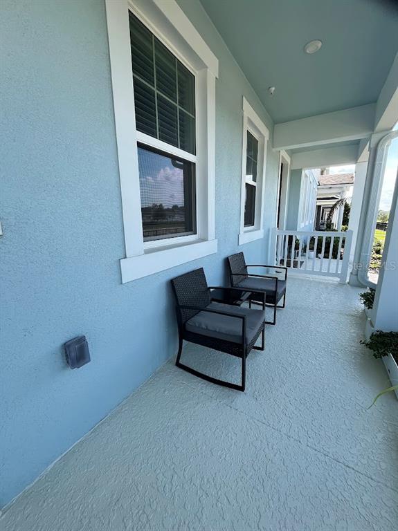 A covered porch with light blue walls features two black wicker chairs and white railings — 4208 SADLER ROAD, APOPKA, FL