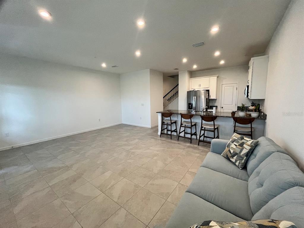 A two-story townhouse exterior features a white garage door, light blue stucco, and beige siding — 4208 SADLER ROAD, APOPKA, FL