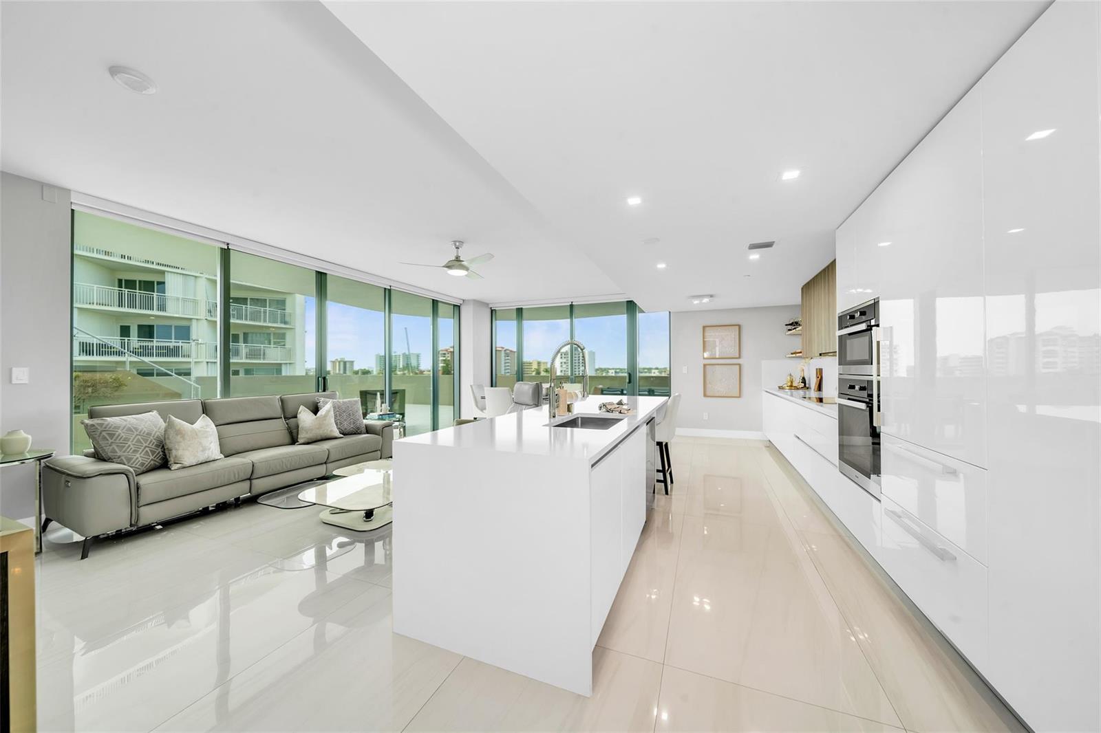 A modern open-concept kitchen and living area with white cabinetry, a large island, and floor-to-ceiling windows — 730 N Ocean Boulevard # 405, Pompano Beach FL 33062, POMPANO BEACH, FL