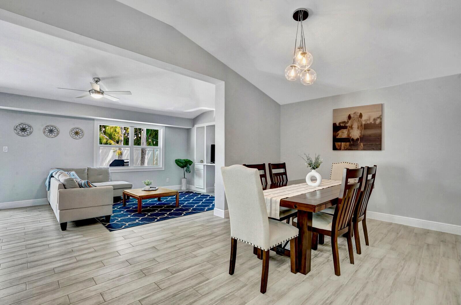 A dining area with a wooden table and chairs opens into a living room space — 1212 Mulberry Place, Wellington FL 33414, WELLINGTON, FL