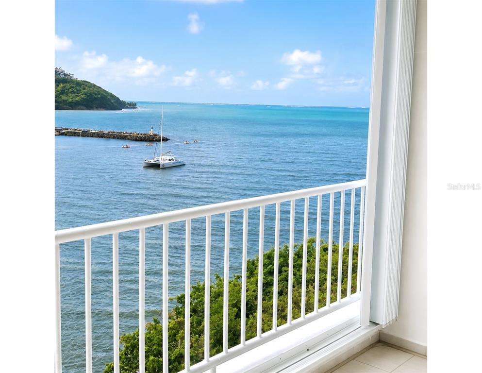 A balcony with a white railing overlooks a bay with a boat and a jetty — DOS MARINAS 4 UNIT 403, FAJARDO, PR