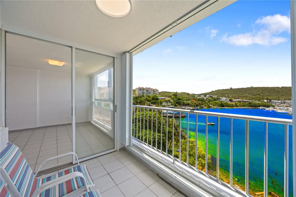 A balcony with tiled flooring and a metal railing overlooks a bright blue bay — DOS MARINAS 4 UNIT 403, FAJARDO, PR
