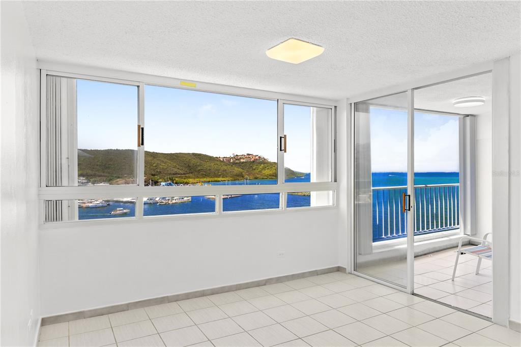 A sunroom with white tile floors, large windows, and a sliding door to a balcony — DOS MARINAS 4 UNIT 403, FAJARDO, PR