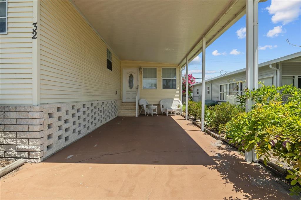 A covered carport leads to the front entrance of a yellow mobile home — 1610 REYNOLDS ROAD Lot 32, LAKELAND, FL