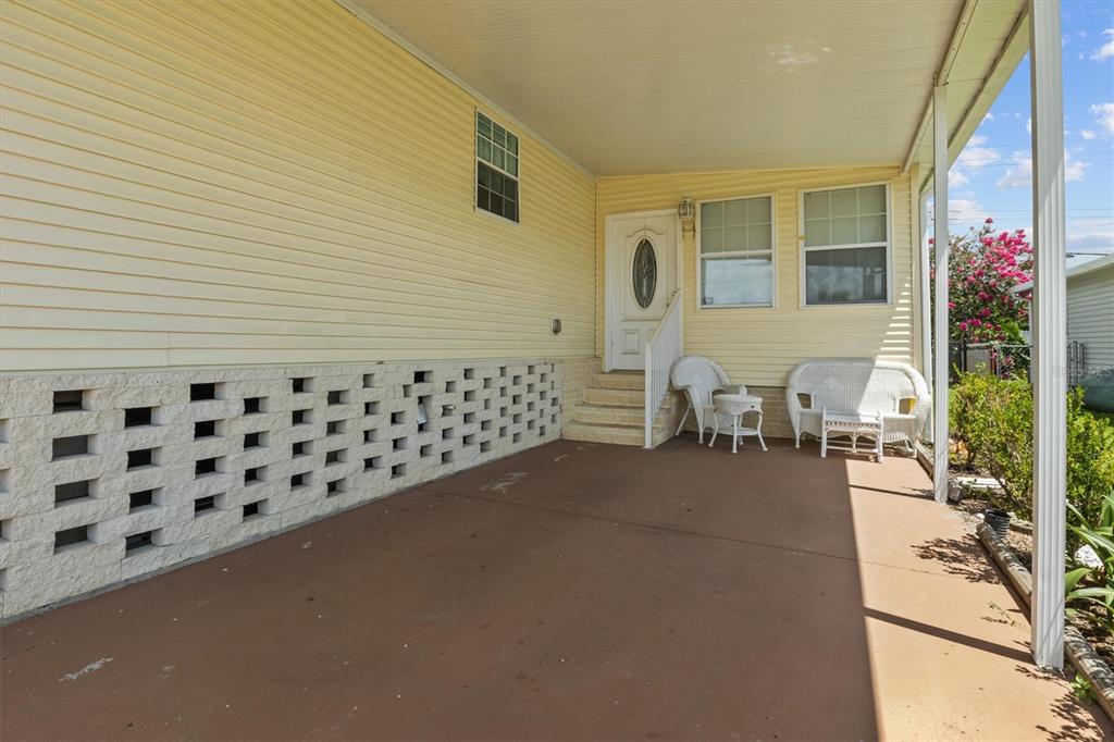 A covered concrete patio features a white door, stairs, and a decorative block wall — 1610 REYNOLDS ROAD Lot 32, LAKELAND, FL