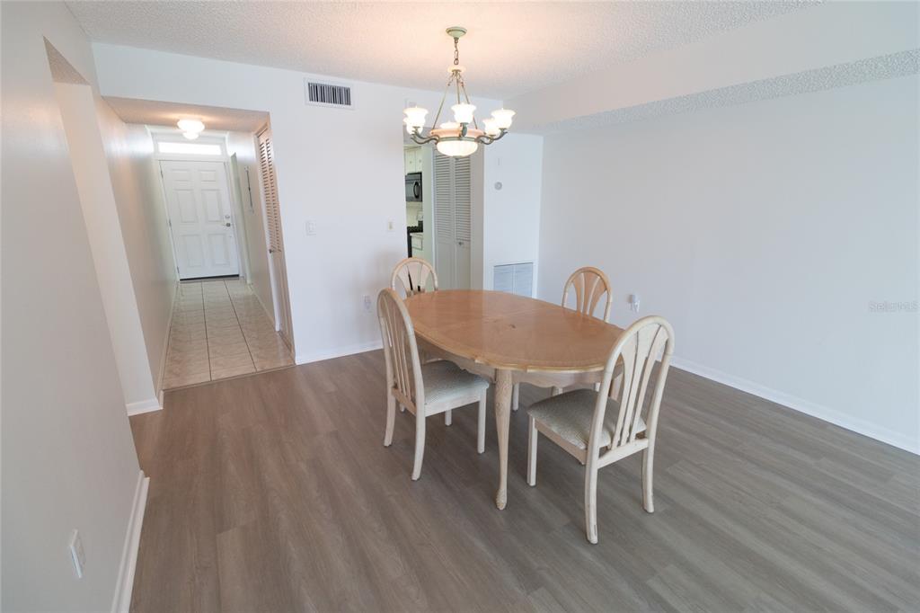 A dining area features a wooden table, four chairs, a chandelier, and light-colored wood flooring — 5980 SHORE BOULEVARD S UNIT 405, GULFPORT, FL