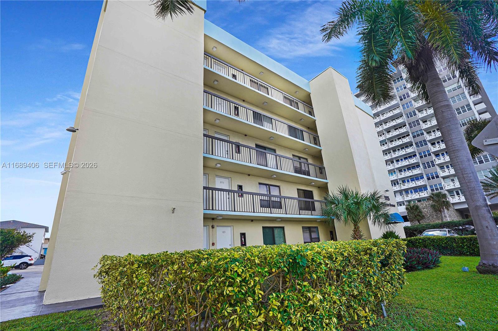 A low-rise apartment building features balconies, a hedge, and a tall palm tree — 3215 N Ocean Dr # 301, Hollywood FL 33019, HOLLYWOOD, FL