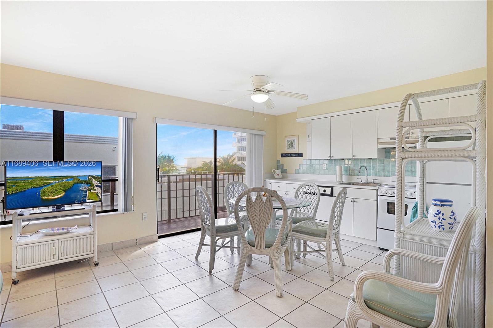 A bright kitchen and dining area features white cabinetry, tile flooring, and a balcony view — 3215 N Ocean Dr # 301, Hollywood FL 33019, HOLLYWOOD, FL