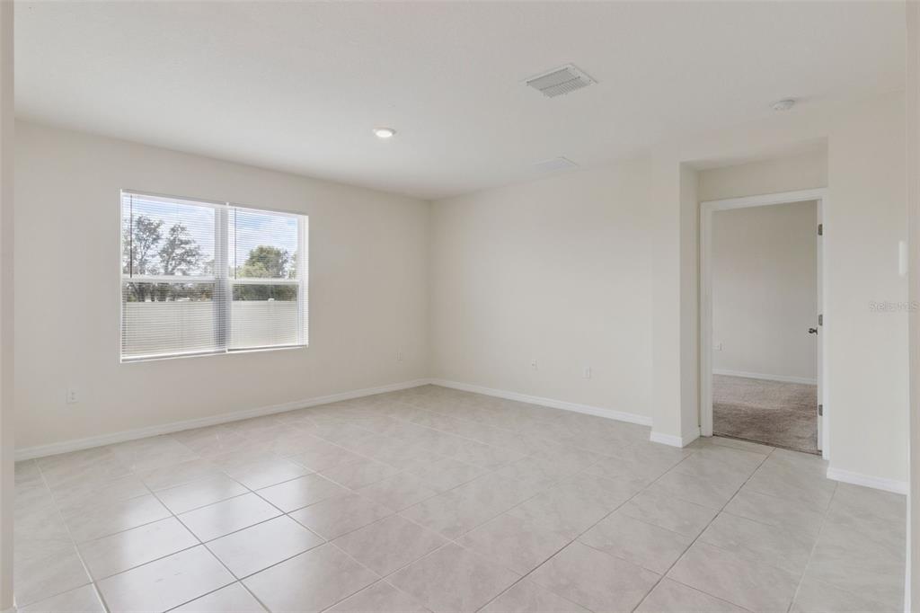 A bright room with light-colored tile flooring, white walls, and a doorway leading to carpet — 4373 DELEON STREET, HAINES CITY, FL
