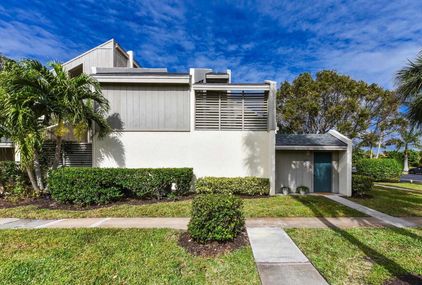 A two-story townhouse exterior with a teal front door, gray siding, and landscaped front yard — 1605 S Us Highway 1, Jupiter FL 33477, JUPITER, FL