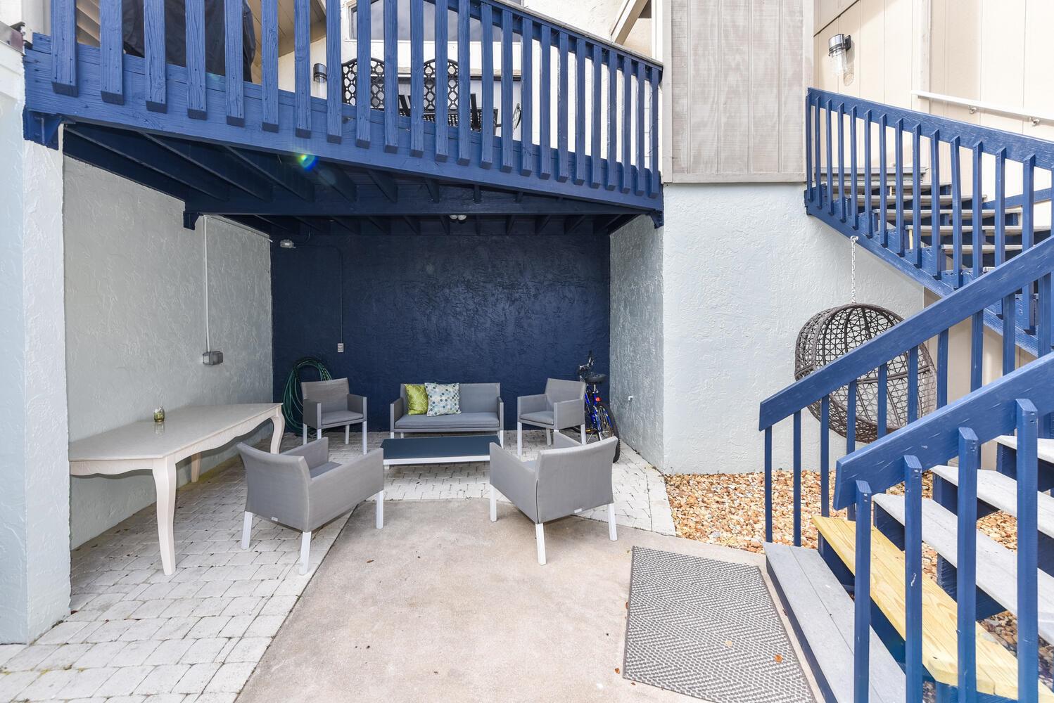 A patio area features gray outdoor furniture, a white table, and blue wooden stairs — 1605 S Us Highway 1, Jupiter FL 33477, JUPITER, FL