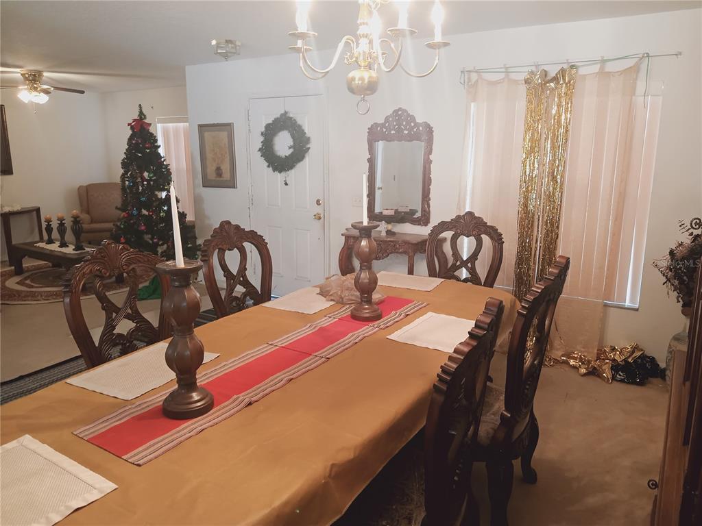 A dining room features a long table, ornate wooden chairs, and a festive Christmas tree — 2474 MALLOW OAK COURT, APOPKA, FL