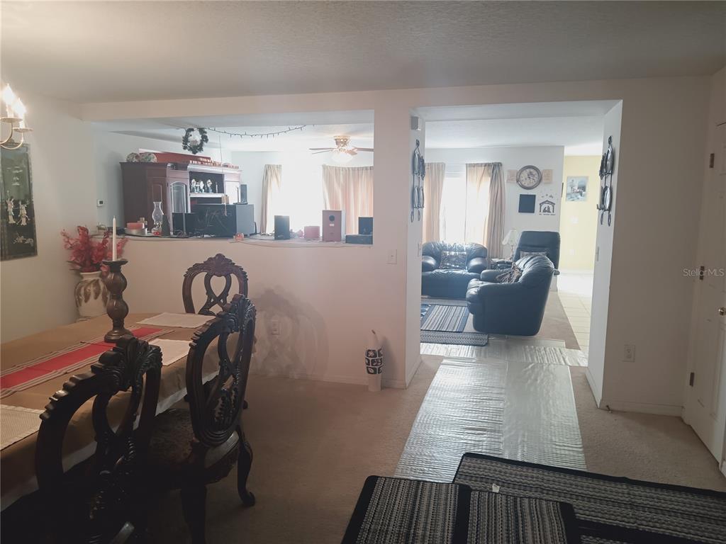 A dining area with ornate chairs opens into a living room with dark leather furniture — 2474 MALLOW OAK COURT, APOPKA, FL