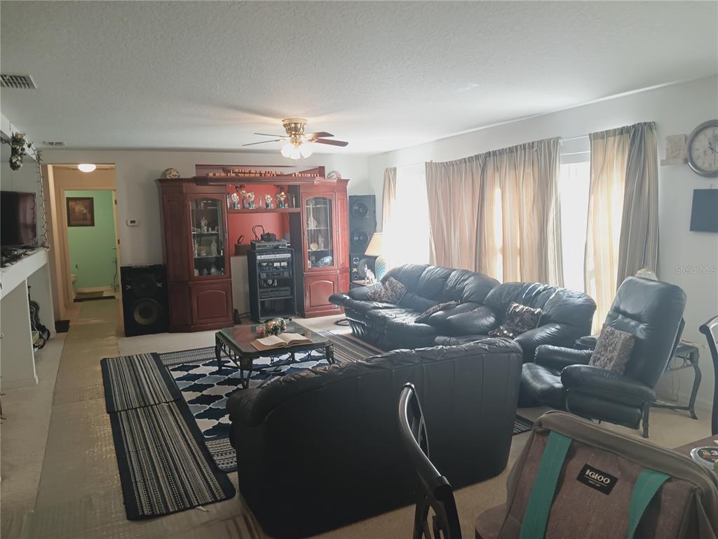 A living room features a large wooden entertainment center, black leather sofas, and a patterned rug — 2474 MALLOW OAK COURT, APOPKA, FL