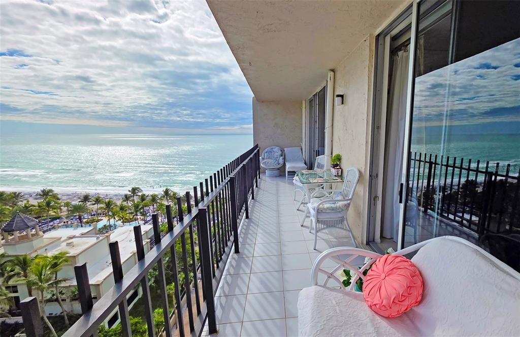 A high-rise balcony features white tile flooring, patio furniture, and a view of the ocean — 1212 BEN FRANKLIN DRIVE UNIT 1205, SARASOTA, FL