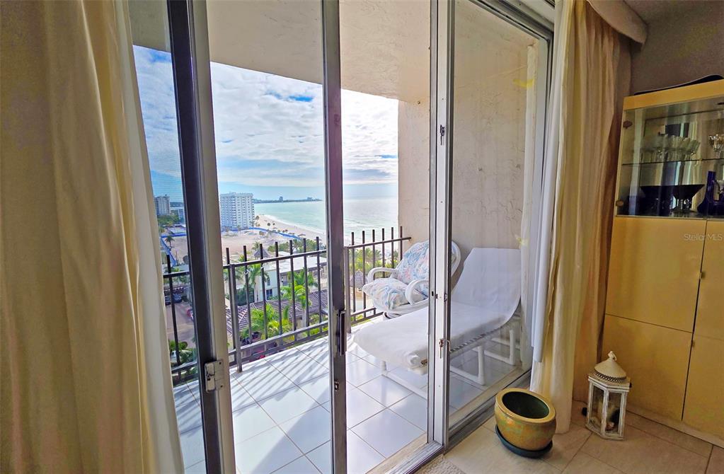 A balcony with a lounge chair overlooks a beach and ocean from a sliding door — 1212 BEN FRANKLIN DRIVE UNIT 1205, SARASOTA, FL