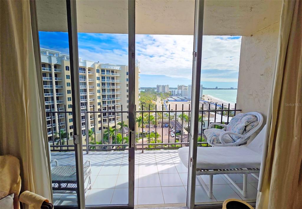 A balcony with white tile flooring overlooks a beach and nearby high-rise buildings — 1212 BEN FRANKLIN DRIVE UNIT 1205, SARASOTA, FL