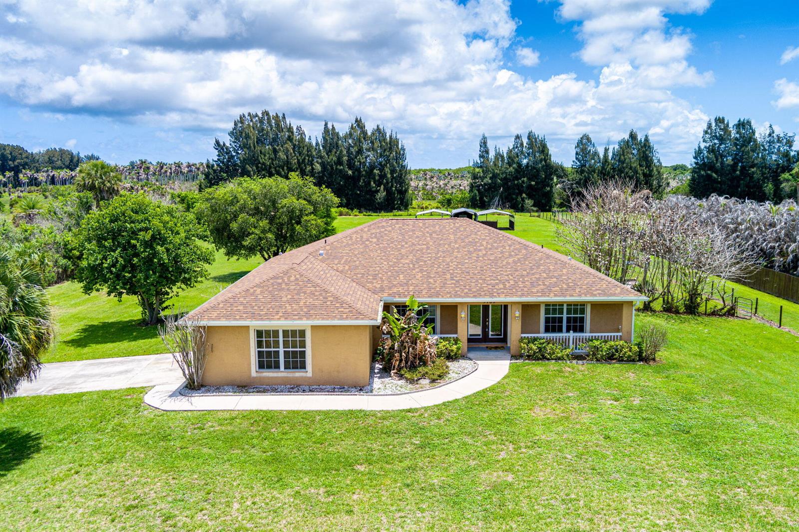 An aerial view of a tan, single-story house with a brown shingled roof and lawn — 3768 Seminole Road, Fort Pierce FL 34951, FORT PIERCE, FL