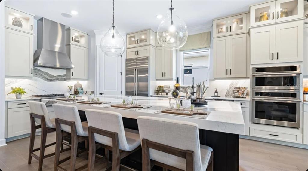 A modern kitchen features white cabinetry, a large marble-topped island, and stainless steel appliances — 10614 ECLIPSE STREET, SARASOTA, FL