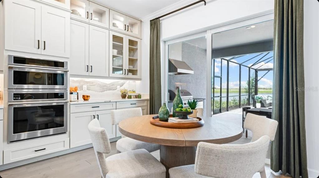 A dining area with a round wooden table, white cabinetry, and sliding doors to a patio — 10614 ECLIPSE STREET, SARASOTA, FL