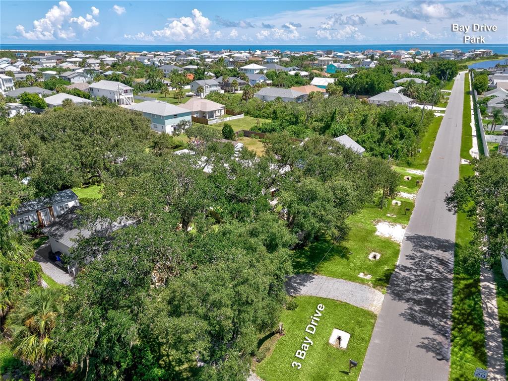 An aerial view shows a residential street with a wooded lot and nearby houses — 3 BAY DRIVE, PALM COAST, FL