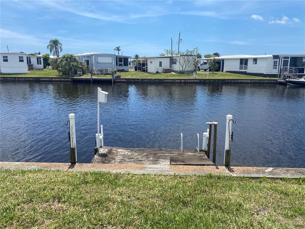 A wooden dock extends into a canal in front of several mobile homes — 508 WINDSOR PLACE, NORTH PORT, FL