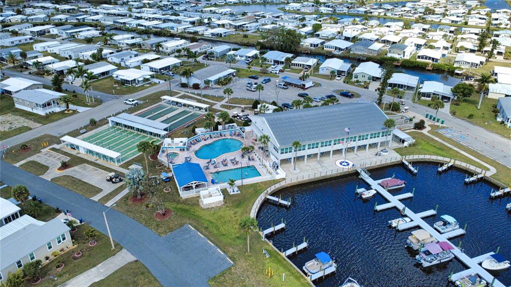 An aerial view shows a community clubhouse with a pool, marina, and surrounding residential homes — 508 WINDSOR PLACE, NORTH PORT, FL