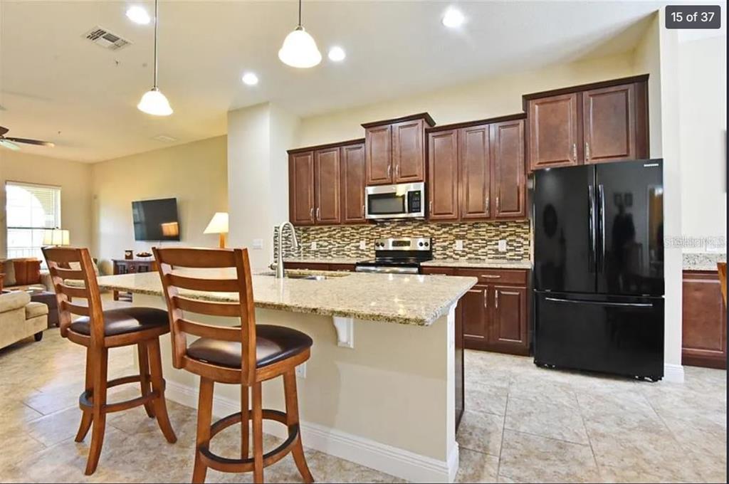 A kitchen features dark wood cabinets, granite countertops, a kitchen island, and a black refrigerator — 3012 PORTA ROMANO WAY, LAKE MARY, FL