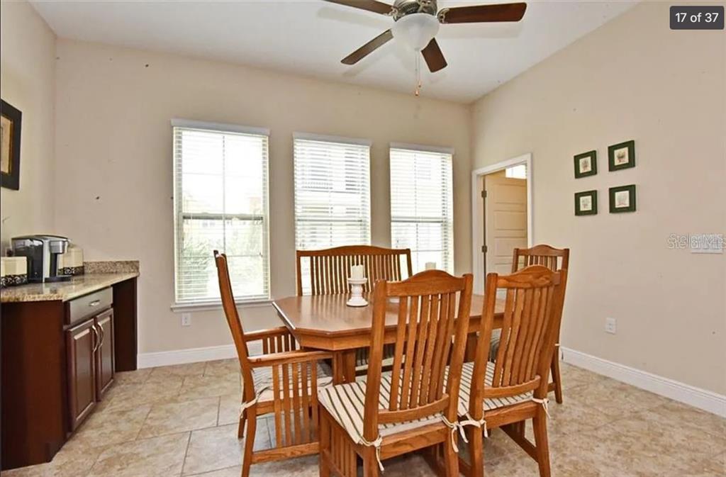 A dining room with a wooden table, chairs, tile flooring, and three windows — 3012 PORTA ROMANO WAY, LAKE MARY, FL