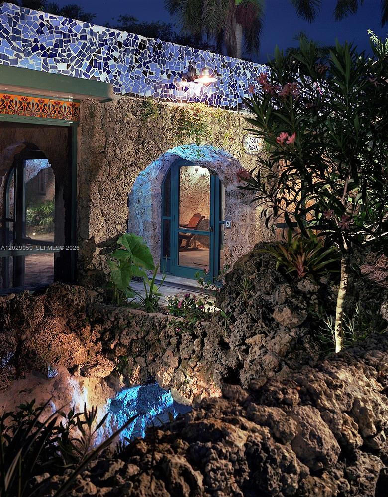 An exterior view of a stone building with a blue mosaic wall and arched doorways — 1301 MILAN AVE # 3, Coral Gables FL 33134, CORAL GABLES, FL