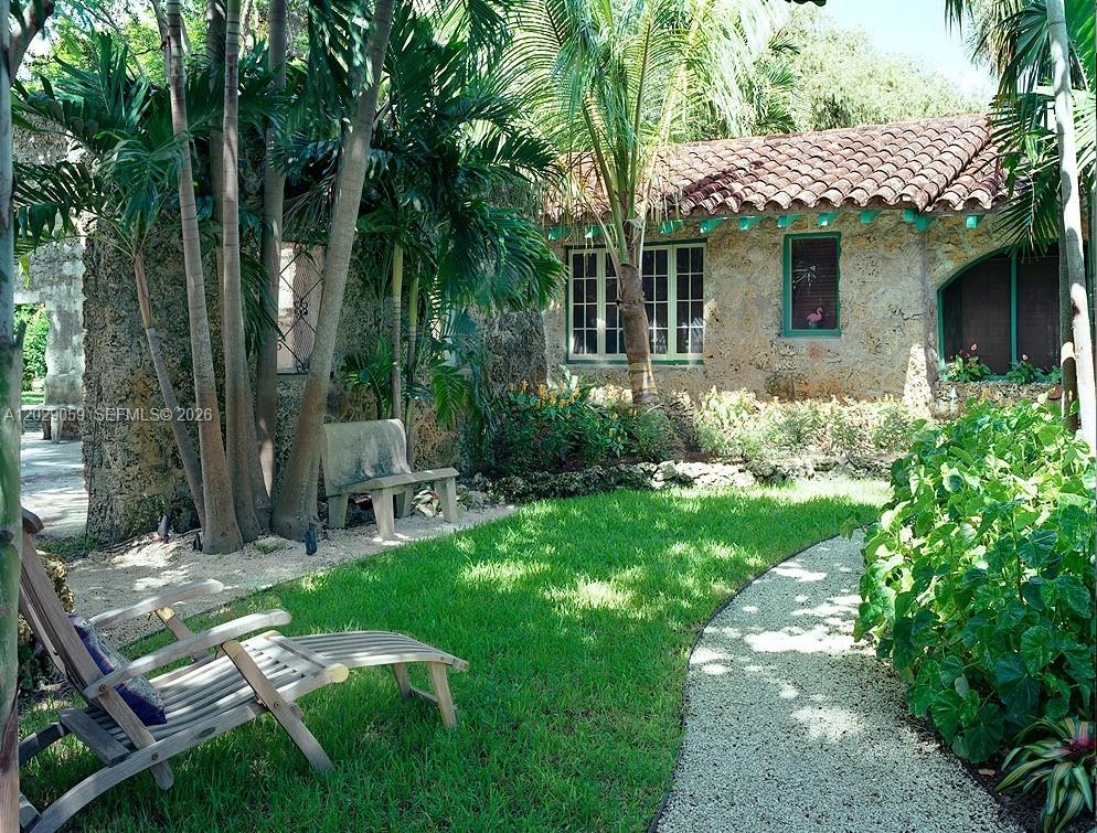 A stone cottage with a tile roof sits beside a grassy lawn and gravel path — 1301 MILAN AVE # 3, Coral Gables FL 33134, CORAL GABLES, FL