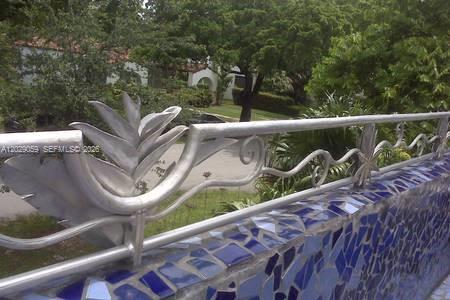 A metal railing with decorative leaf designs sits atop a blue mosaic tile wall — 1301 MILAN AVE # 3, Coral Gables FL 33134, CORAL GABLES, FL