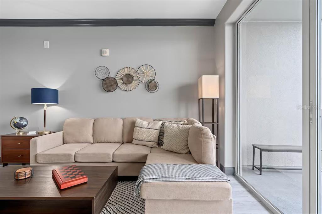 A living room features a beige sectional sofa, a wooden coffee table, and wall decor — 13415 BLUE HERON BEACH DRIVE UNIT 706, ORLANDO, FL