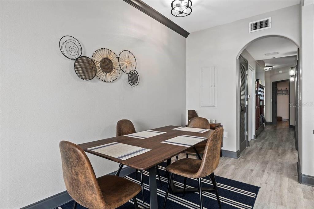 A dining area features a wooden table, four chairs, a striped rug, and wall art — 13415 BLUE HERON BEACH DRIVE UNIT 706, ORLANDO, FL