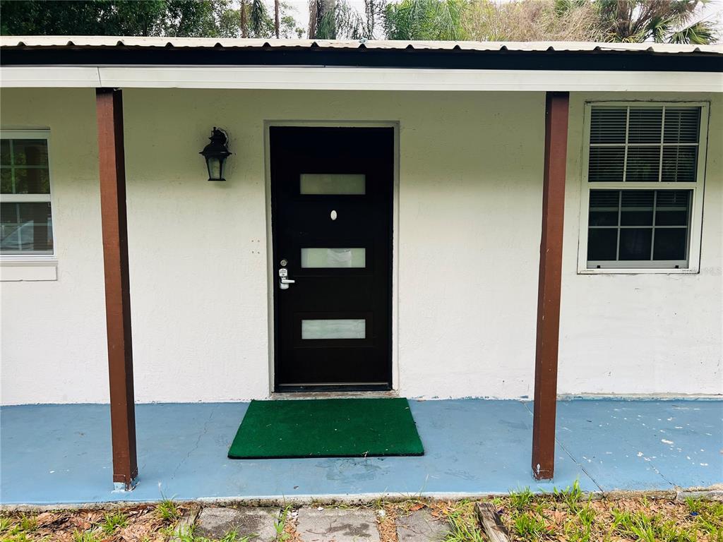A black front door with three horizontal glass panels sits on a covered porch — 1218 KINGSTON AVENUE, ORLANDO, FL