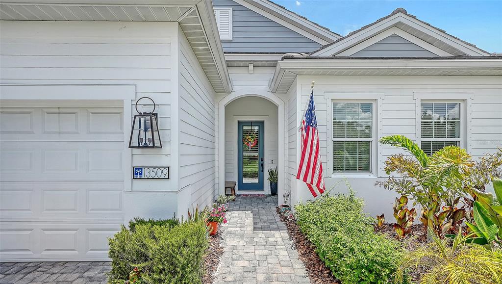 The exterior of a house features a white garage, a blue front door, and landscaping — 13509 DEEP BLUE PLACE, BRADENTON, FL