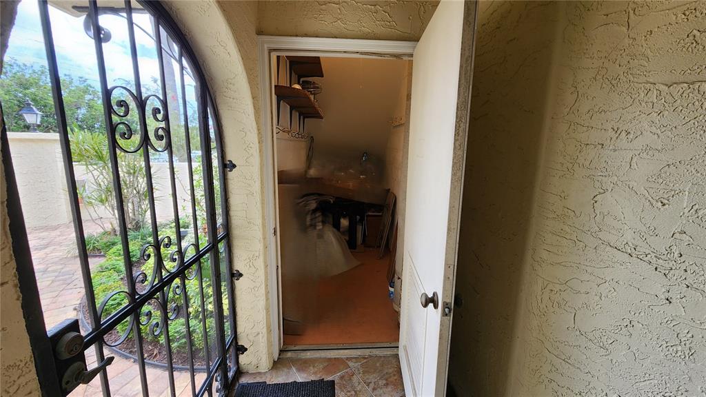 An open door reveals a small storage room with shelves next to an outdoor gate — 6101 34TH STREET W UNIT 10A, BRADENTON, FL