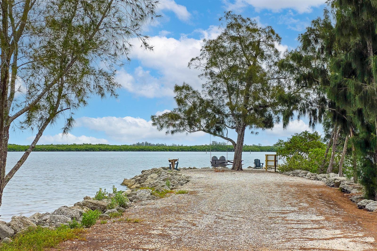 A gravel path leads to a waterfront area with a tree, swing, and chairs — 3586 Lucia Drive, Vero Beach FL 32967, VERO BEACH, FL