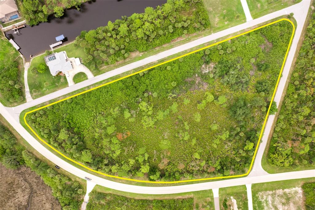An aerial view shows a vacant, triangular-shaped lot bordered by two curved roads — 12518 EISENHOWER DRIVE, PORT CHARLOTTE, FL
