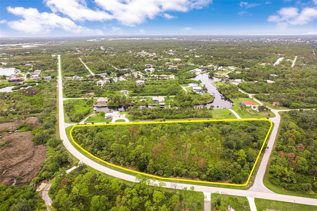 An aerial view shows a large, undeveloped, triangular-shaped plot of land surrounded by trees — 12518 EISENHOWER DRIVE, PORT CHARLOTTE, FL